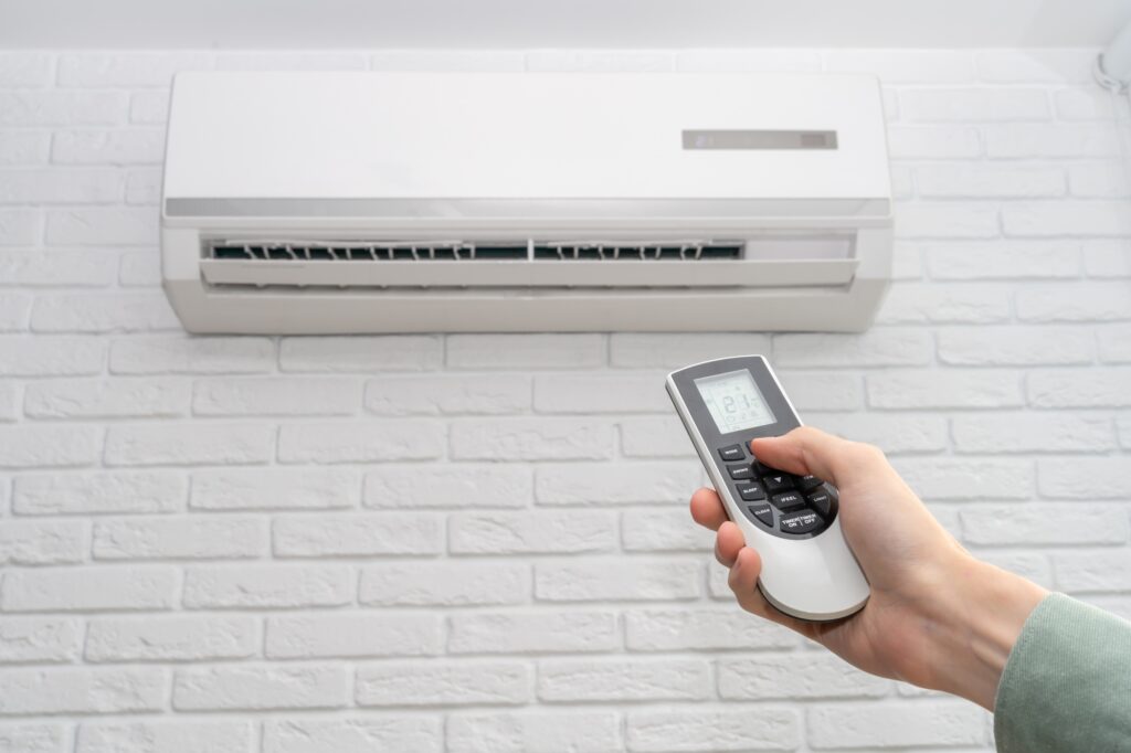 home air conditioner and man hand with remote control closeup
